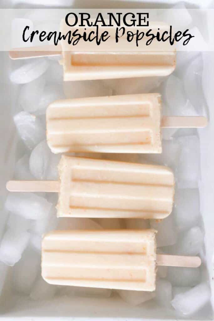 overhead photo of four orange creamsicle popsicles in a white dish full of ice