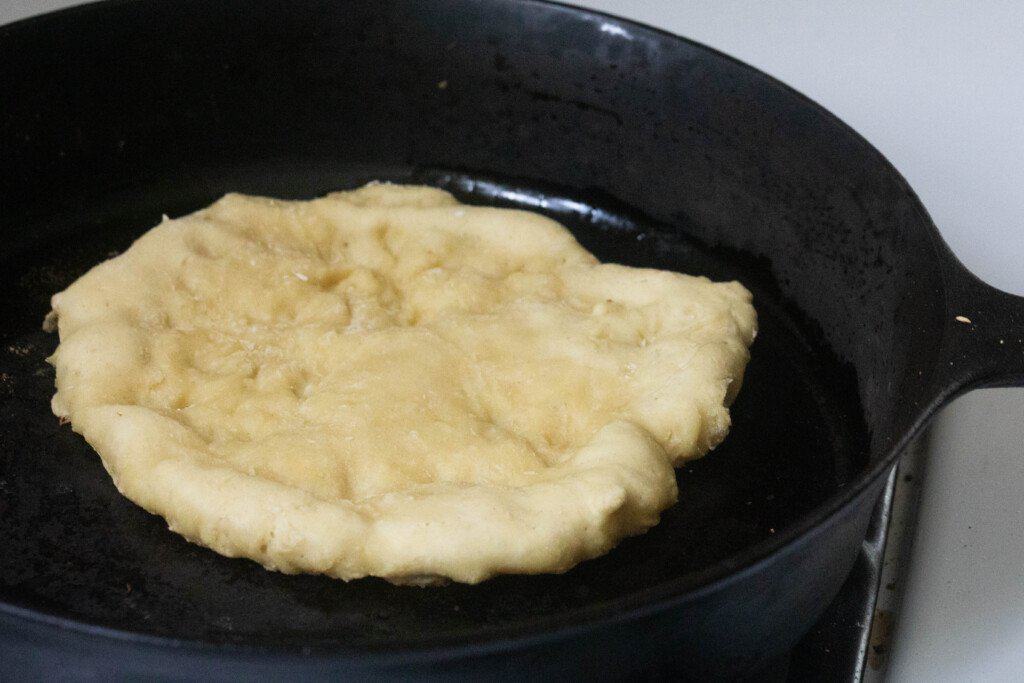 einkorn flat bread frying on a cast iron skillet with oil