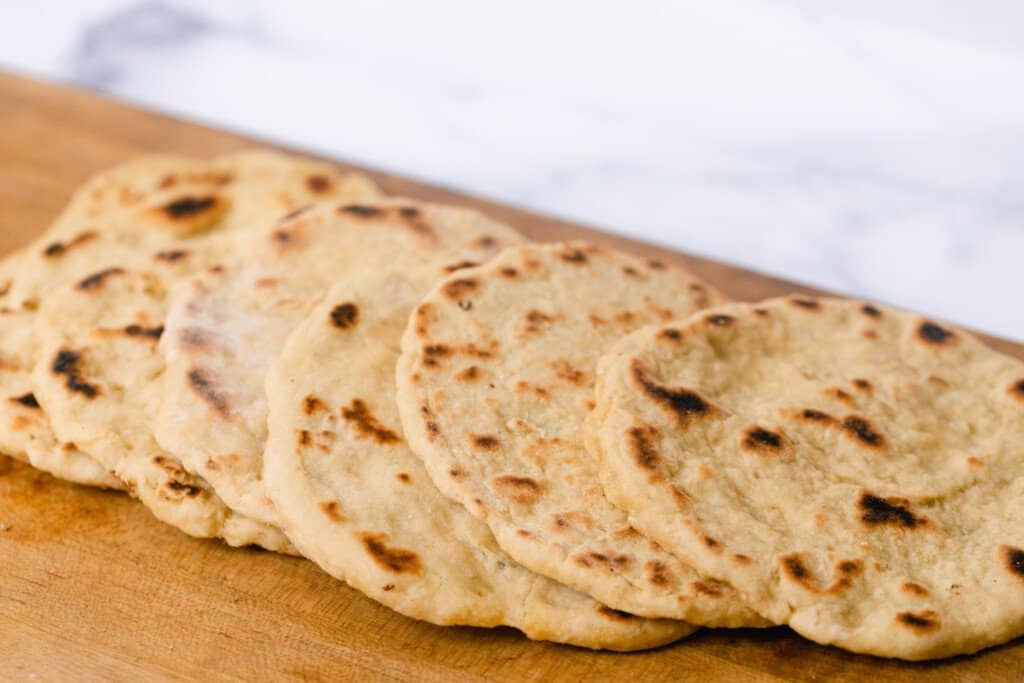 einkorn flat breads spread out in a row on a wooden cutting board 