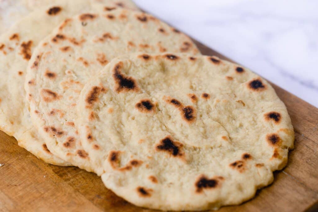 einkorn flat bread layer on out a wood cutting board on top of a white and gray quarts countertop