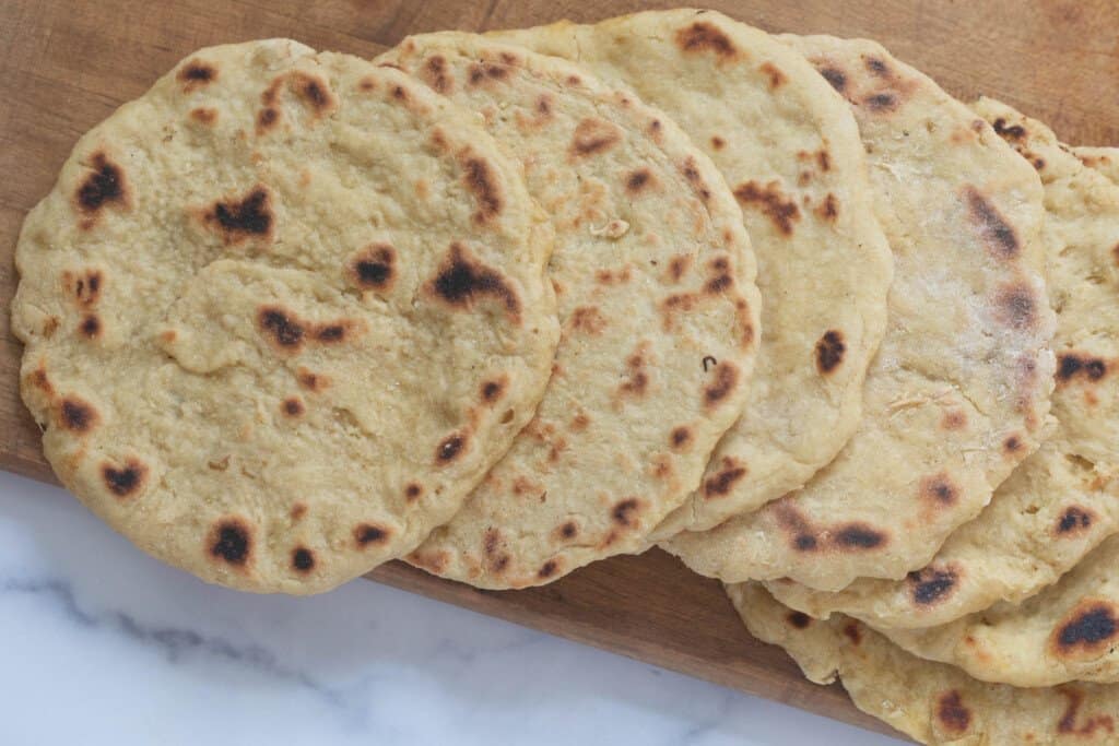 6 einkorn flatbreads spread on a wood cutting board sitting on a white quartz countertop