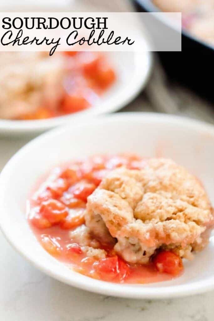 sourdough cherry cobbler in a white bowl with another bowl of cobbler in the background