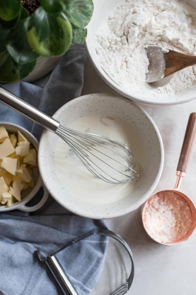 sourdough shortcake cake ingredients: wet ingredients in one bowl with a whisk an and another bowl of dry ingredients on a white countertop