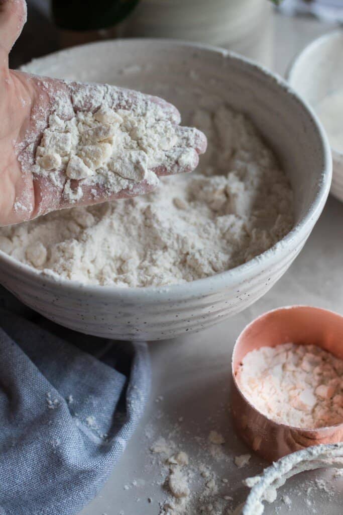 hand holding flour cut into butter to show the size the butter pieces should be when making shortcake