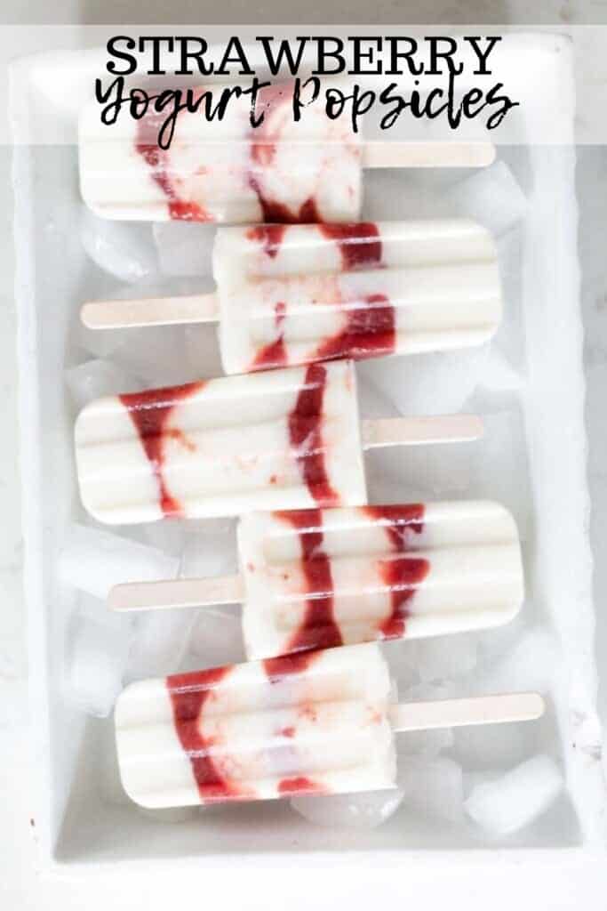 five strawberry yogurt popsicles laying on top of ice cubes in a white dish