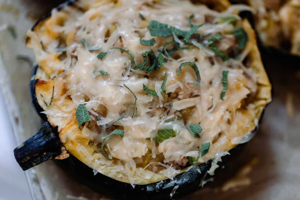 close up picture of sausage and apple stuffed acorn squash topped with Parmesan and fresh sage