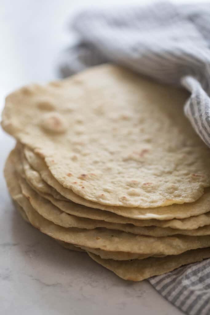 einkorn tortillas stacked up and wrapped in a white and gray stripped towel