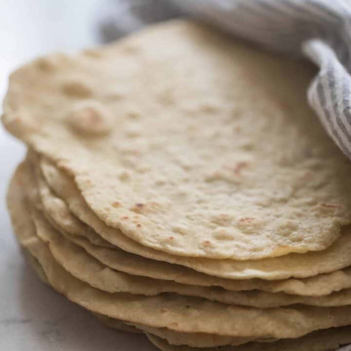 einkorn tortillas stacked up and wrapped in a white and gray stripped towel
