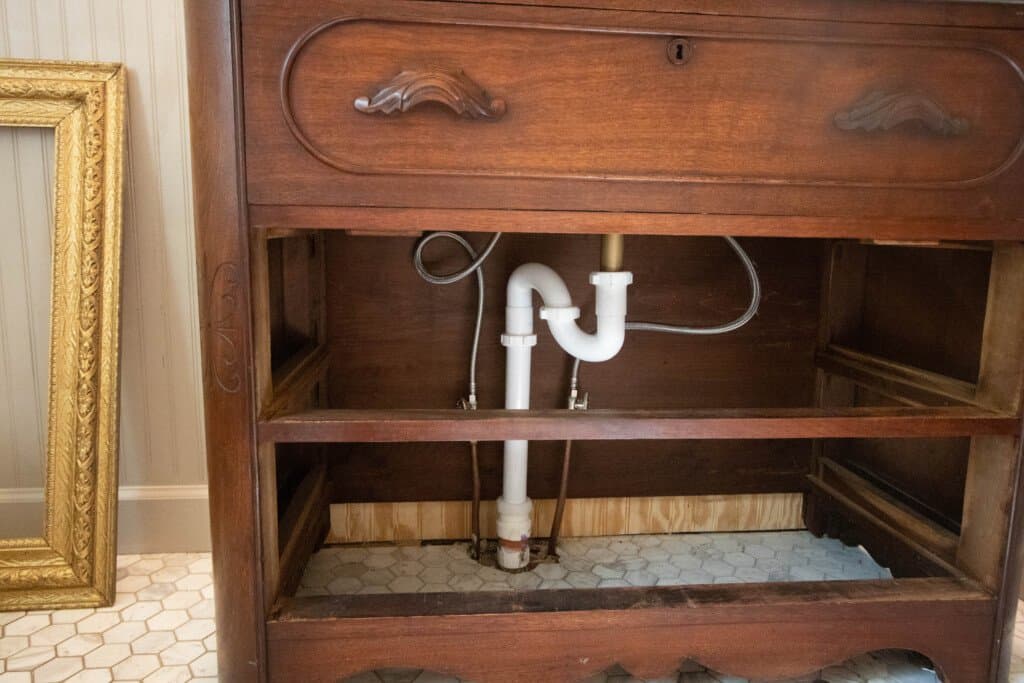 close up picture of a vintage dresser plumbed in a bathroom to create a vanity.