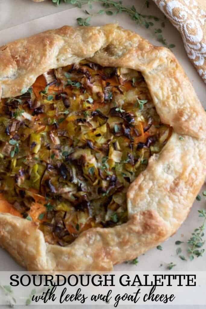 overhead photo of a sourdough galette with leeks and sweet potatoes on a marble countertop with herbs sprinkled around