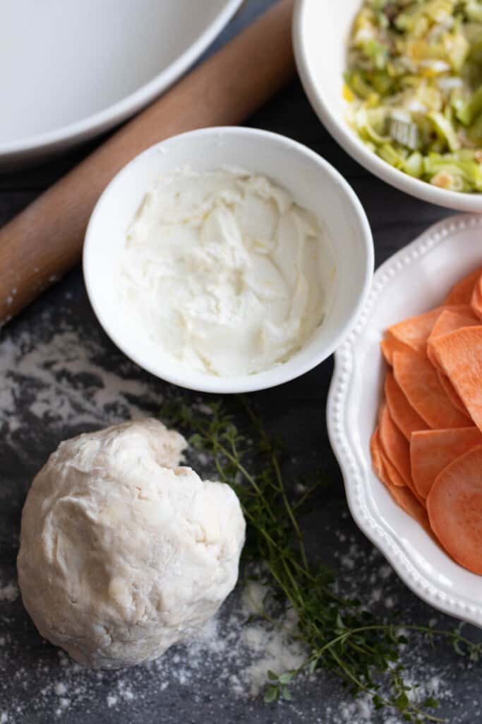 sourdough leek and sweet potato galette ingredients in bowls on a countertop with a rolling pin