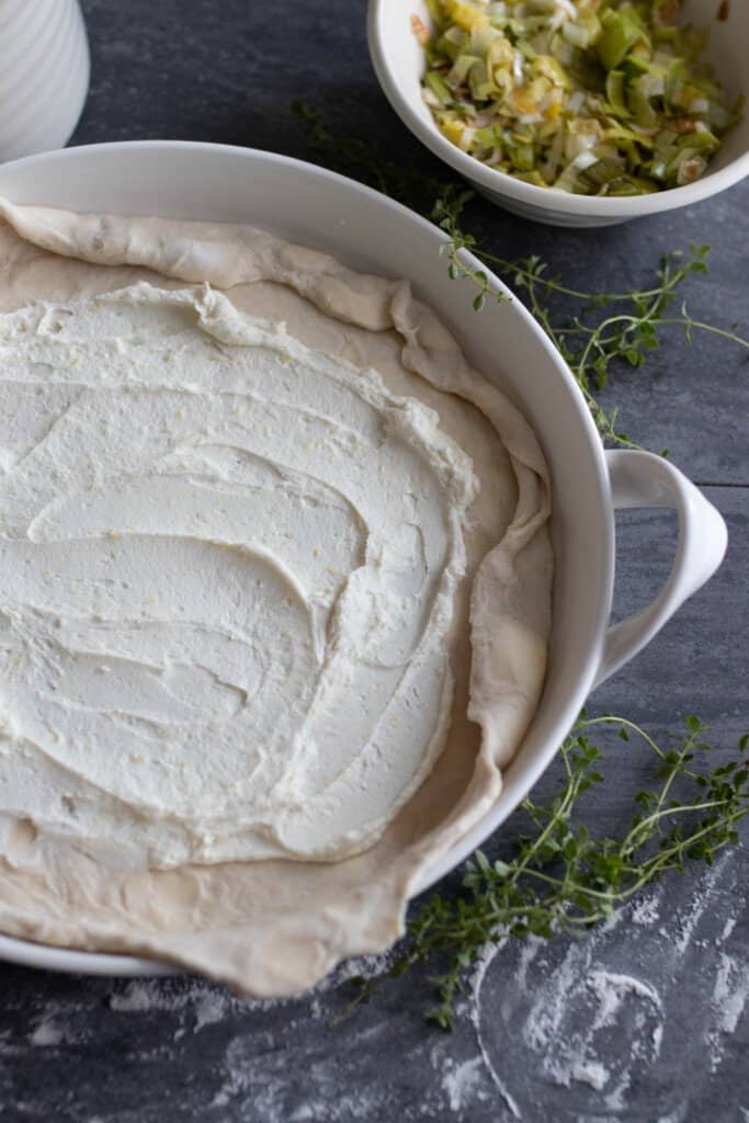 sourdough pie dough rolled out and spread with goat cheese, heavy cream, and lemon zest