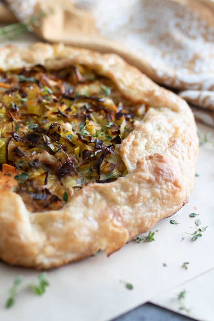 savory sourdough galette on a marble countertop with fresh thyme sprinkled around. A towel is in the background