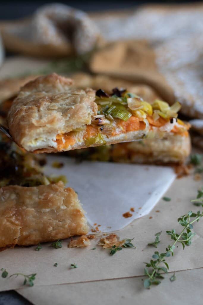 side view of a slice of sourdough galette with leeks and sweet potatoes with the rest of the galette in the background