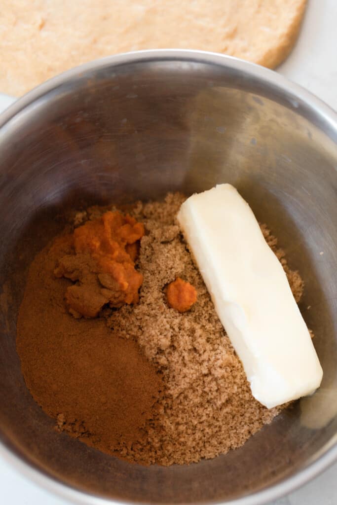 a bowl with softened butter, pumpkin puree, brown sugar, and pumpkin spice