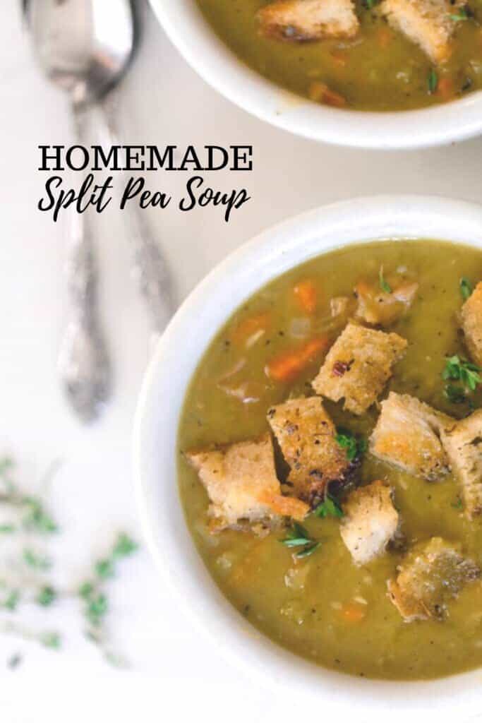 two white bowls filled with split pea soup with carrots and sourdough croutons on a white quartz countertop with fresh thyme and two spoons to the left of the bowls