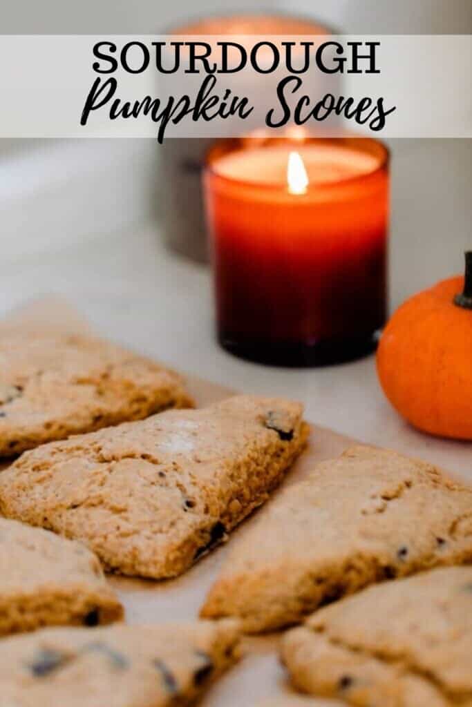 sourdough pumpkin scones cut into triangles on a quarts counter top with lit candles in the background