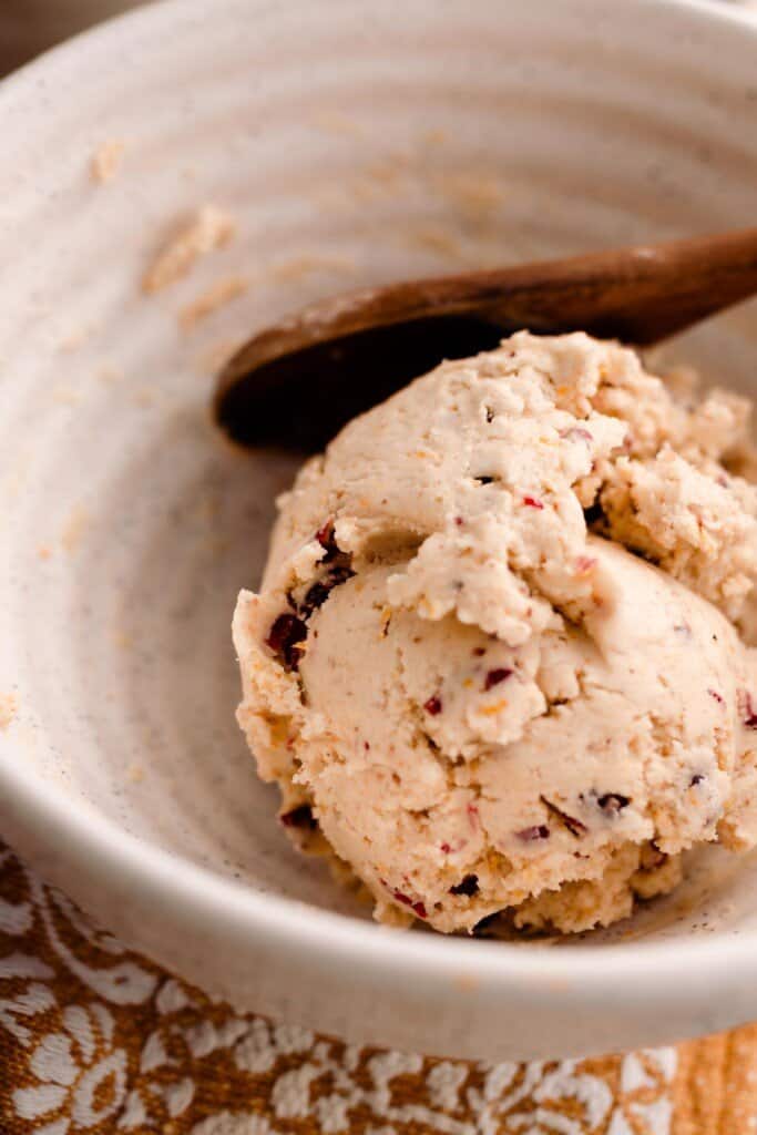 cranberry orange shortbread cookie dough rolled in a bowl with a wooden spoon on a orange and white towel