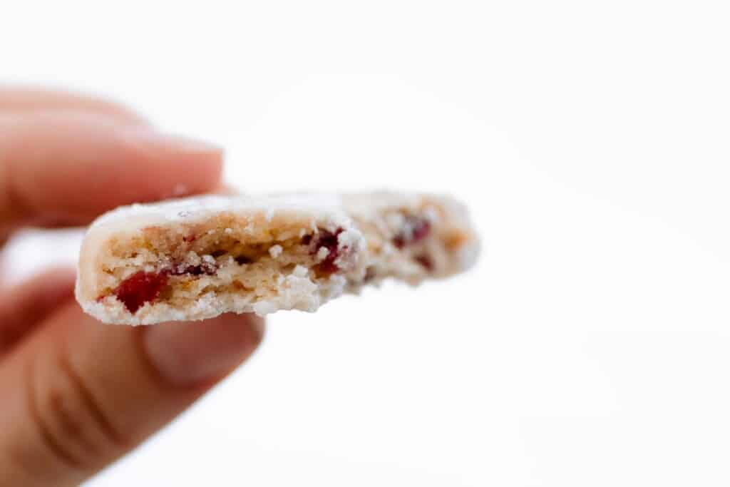 hand holding a cranberry orange cookie coated with powered sugar