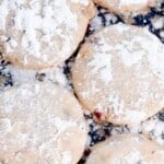 five cranberry orange shortbread cookies dusted with powdered sugar on a black countertop