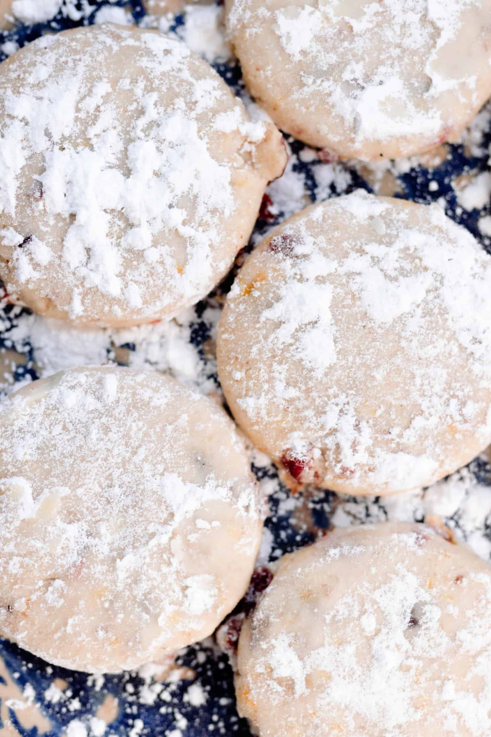 five cranberry orange shortbread cookies dusted with powdered sugar on a black countertop