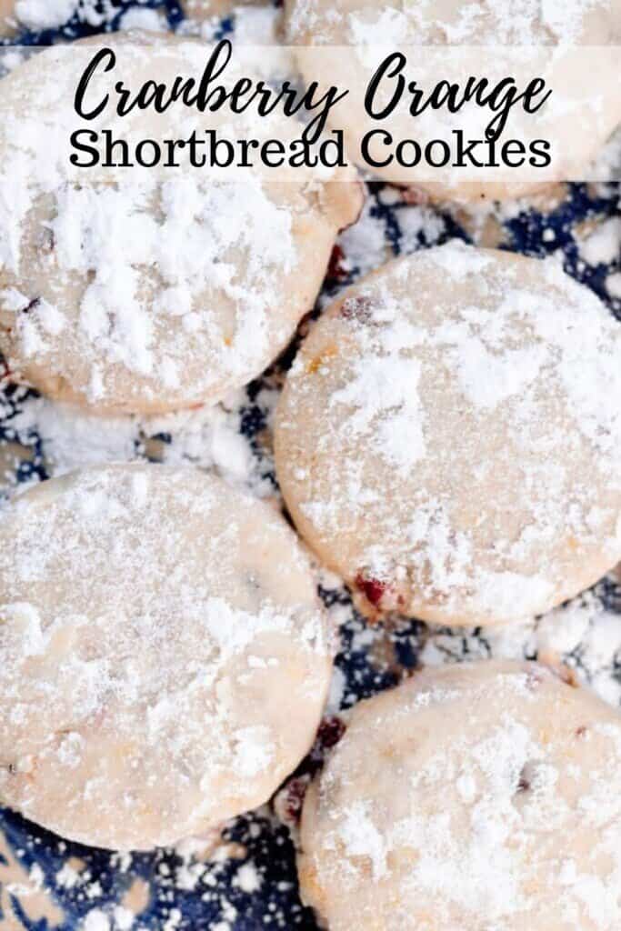 five cranberry orange shortbread cookies dusted with powdered sugar on a black countertop