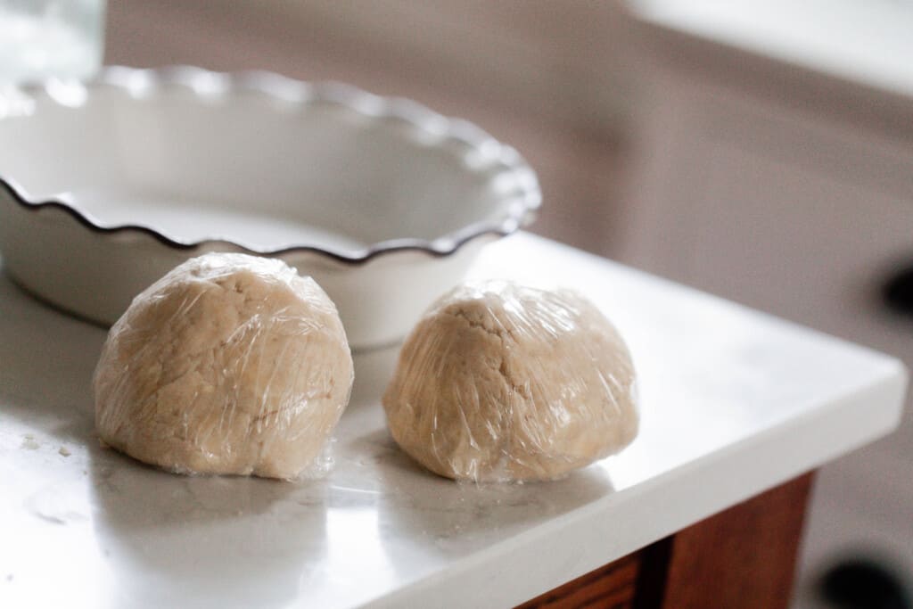 two balls of einkorn pie crust on a white countertop with a pie dish in the background