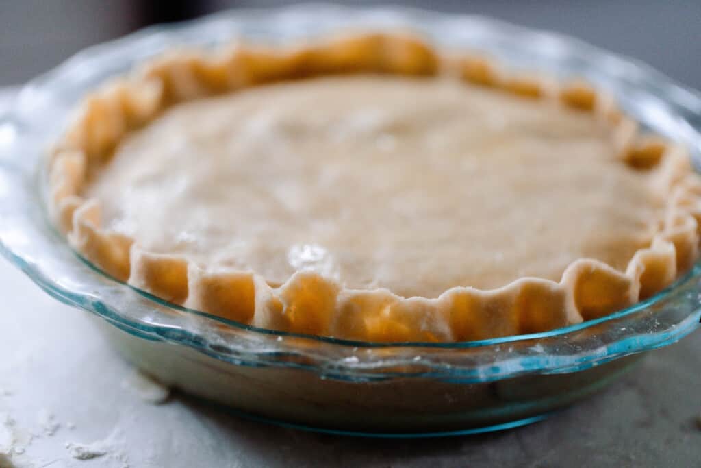 side view of a glass baking dish with a pie made with einkorn pie dough on a countertop