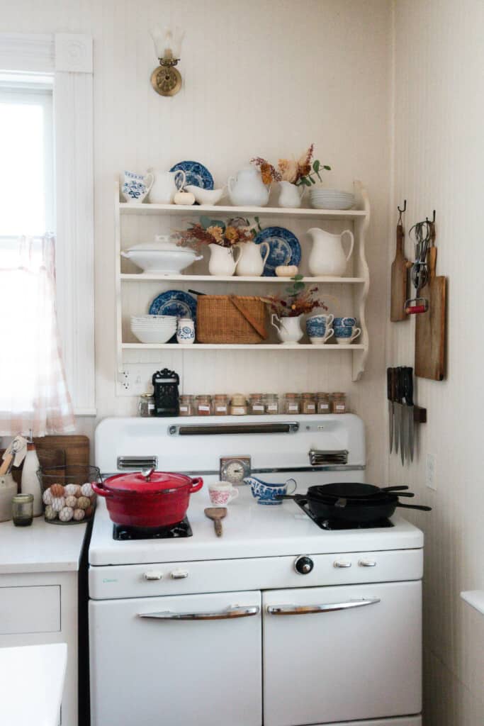 dried flowers in pitches on a antique shelf above and white antique stove