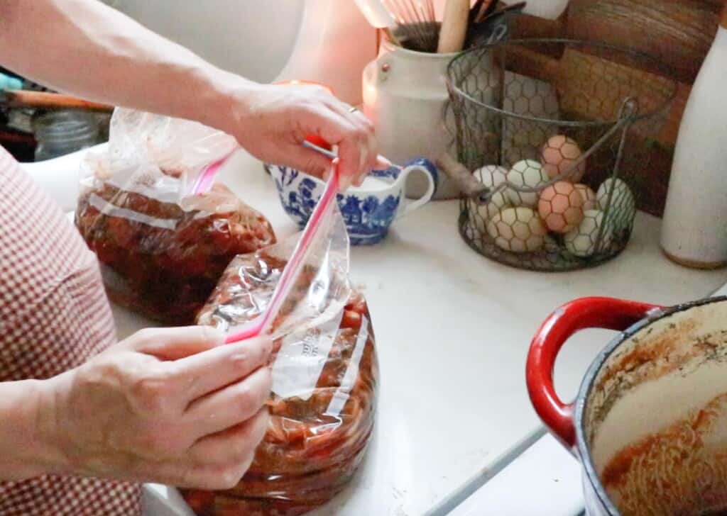 homemade beef chili in a ziplock bag being closed to place in the freezer