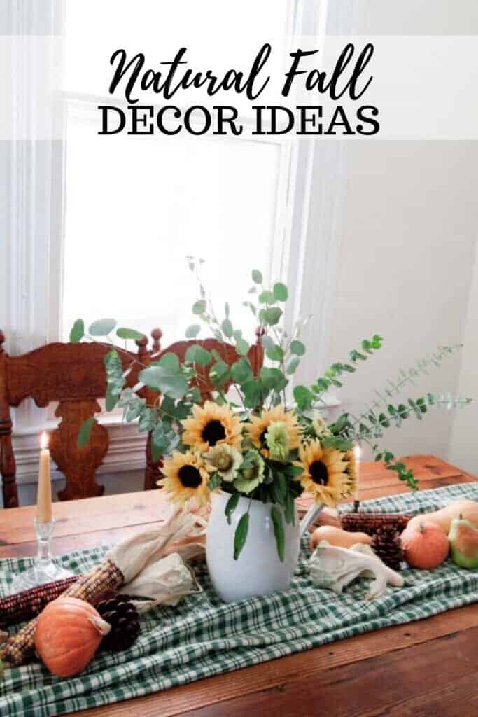 a vintage wood table with a green checked table runner topped with pumpkins, Indian corn, and a vase full of eucalyptus and sunflowers