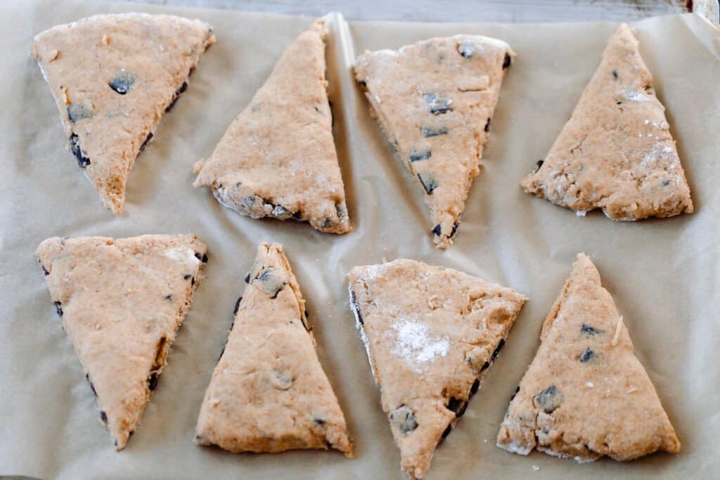 unbaked sourdough pumpkin scones cut into triangles and layer on a parchment lined baking sheet