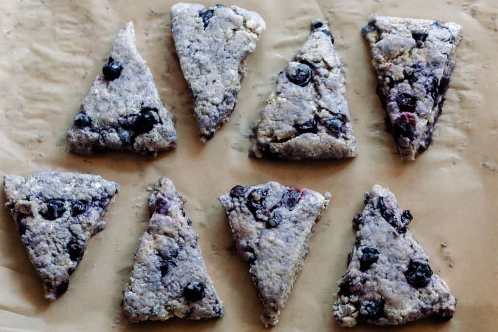 sourdough scone dough cut into 8 equal triangles and laid on piece of parchment paper