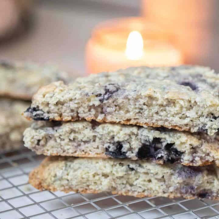 three sourdough scones with blueberries stacked up on a wire rack on a white countertop