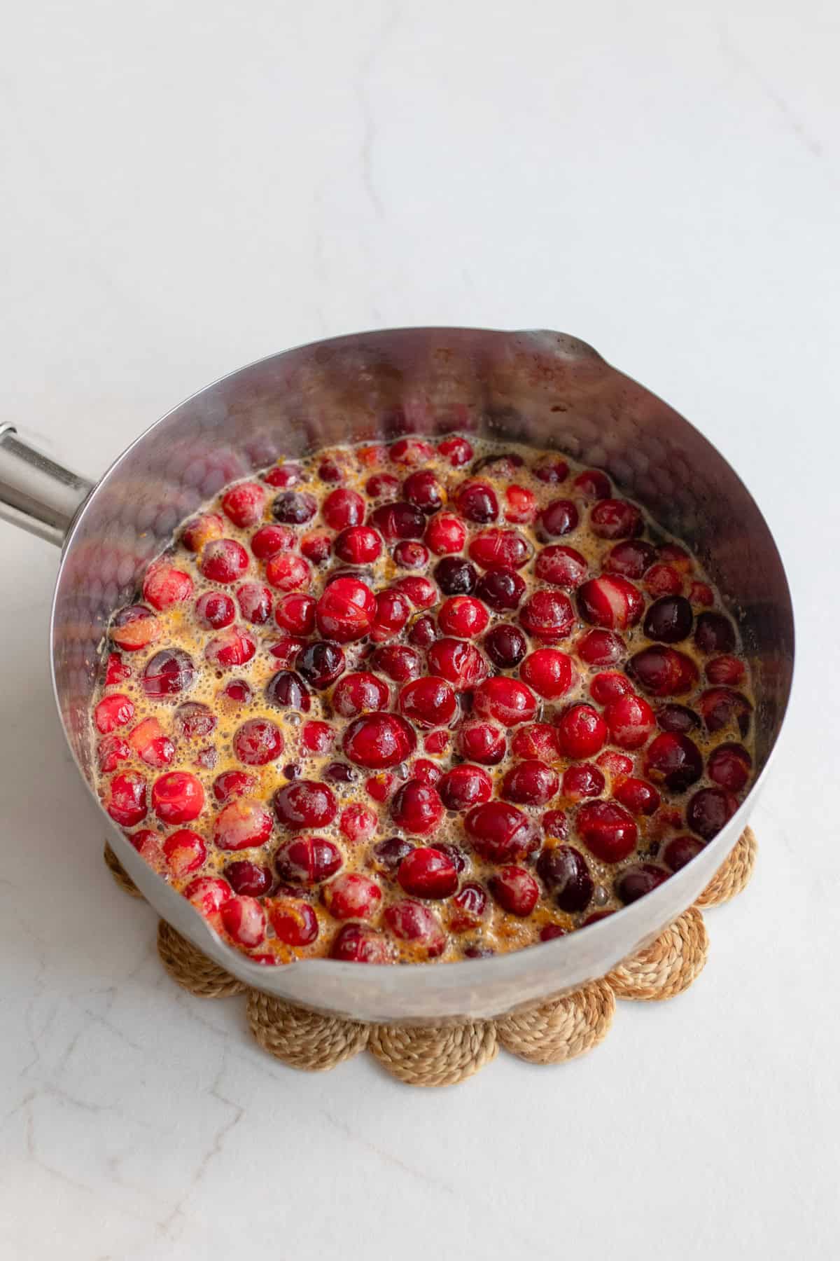 Cranberry mixture boiling on the stove until the berries split open.