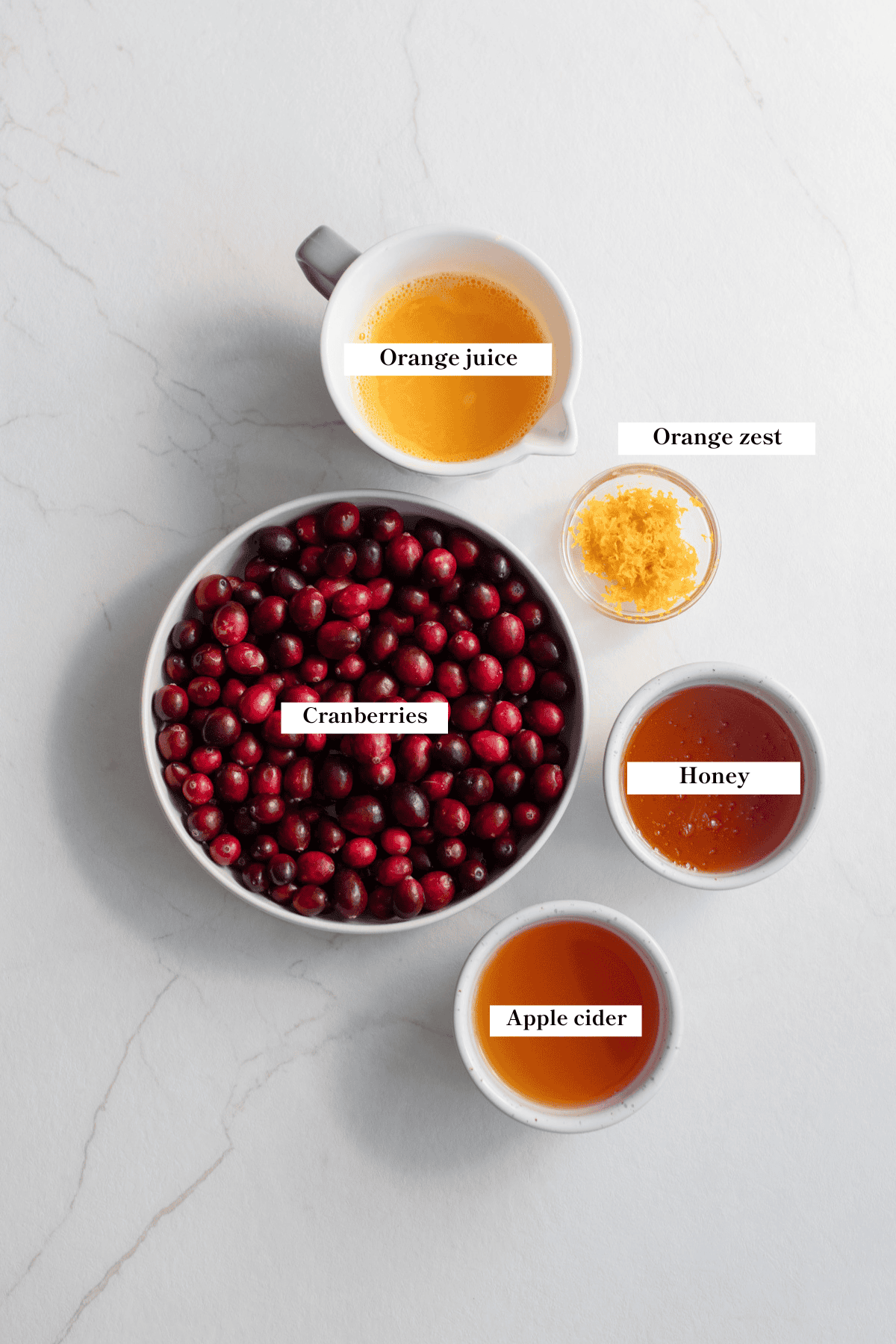 cranberries, orange juice, honey, and apple cider on the counter.