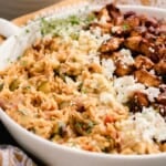 side view of a white dish with Greek orzo with layers of feta, chicken, and olives