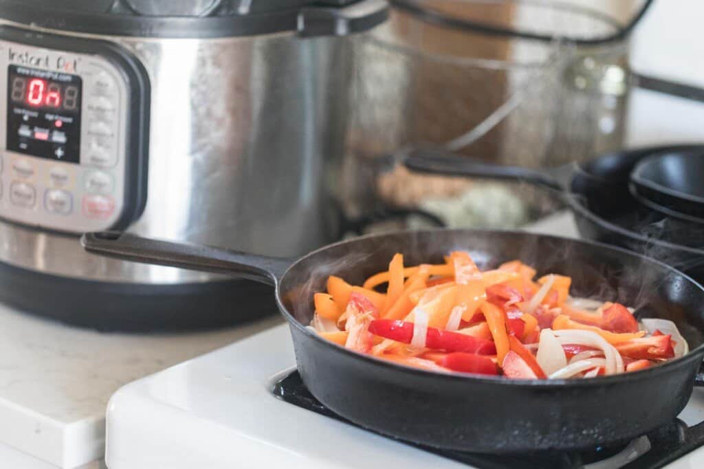 peppers and onions cooking in a cast iron skillet