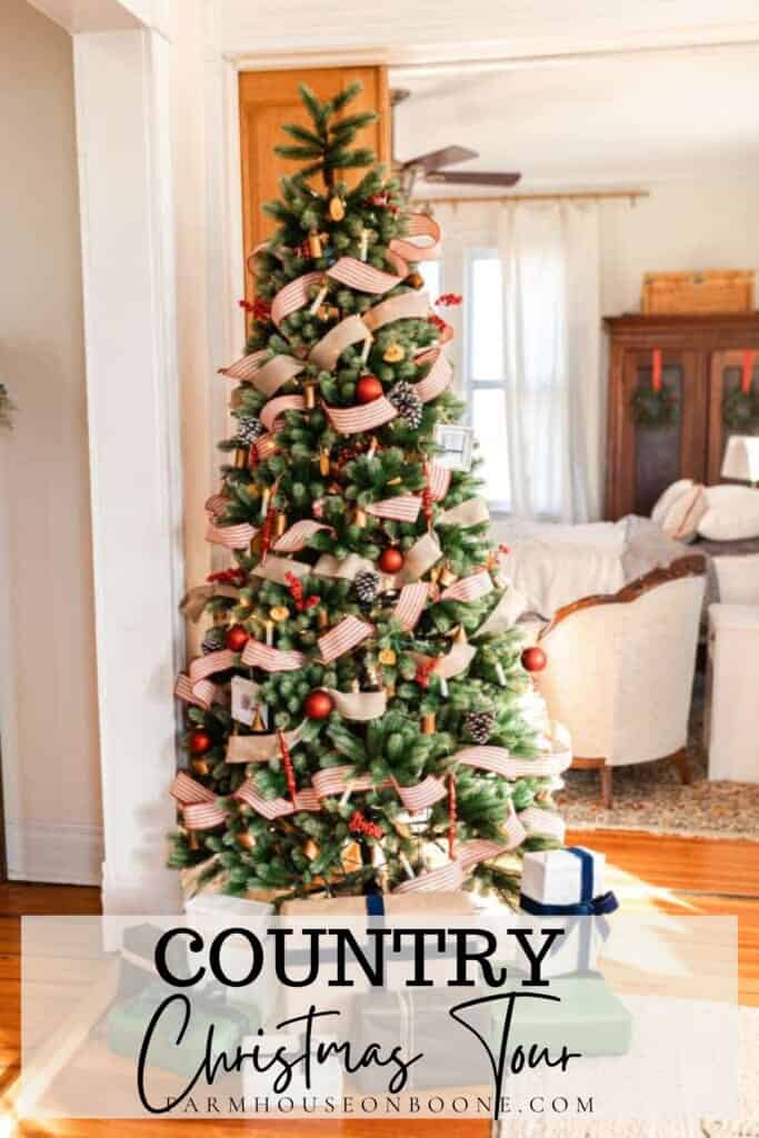 Christmas tree with red and white ticking strip ribbon and burlap ribbon wrapped around, and a variety of ornaments with a living room in the background