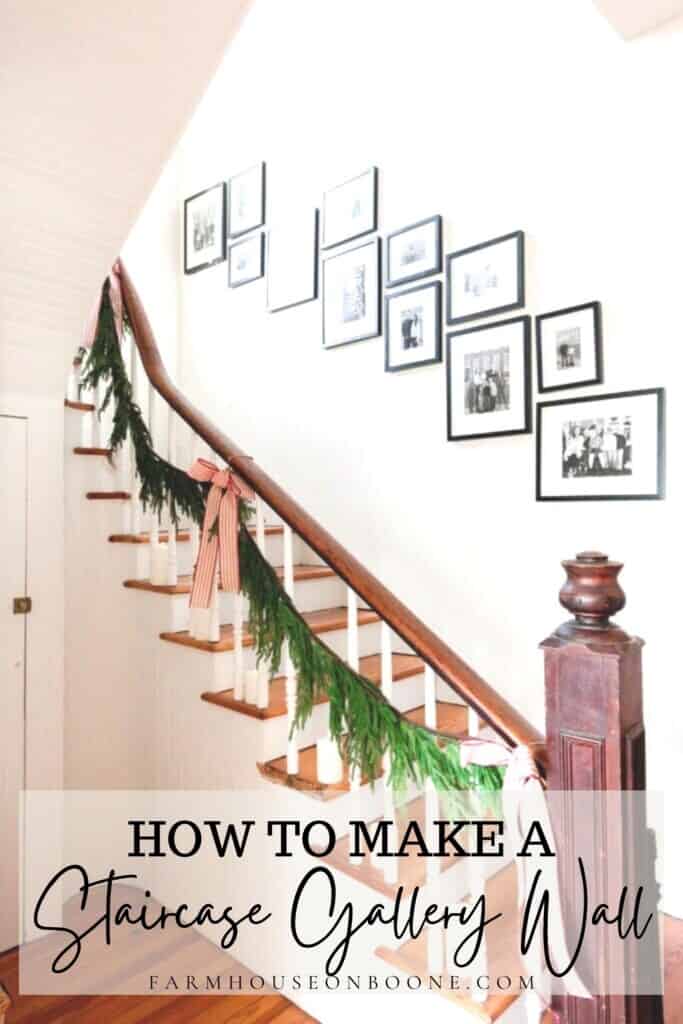 a vintage farmhouse staircase decorated for Christmas with greenery, ribbon, and candles. A gallery wall with black frames and black and white pictures go up the staircase wall
