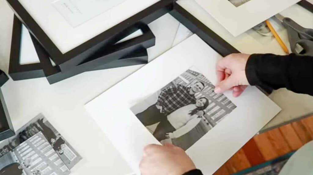 a black and white picture of a couple being secured onto a white backing of a picture frame with more frames behind it