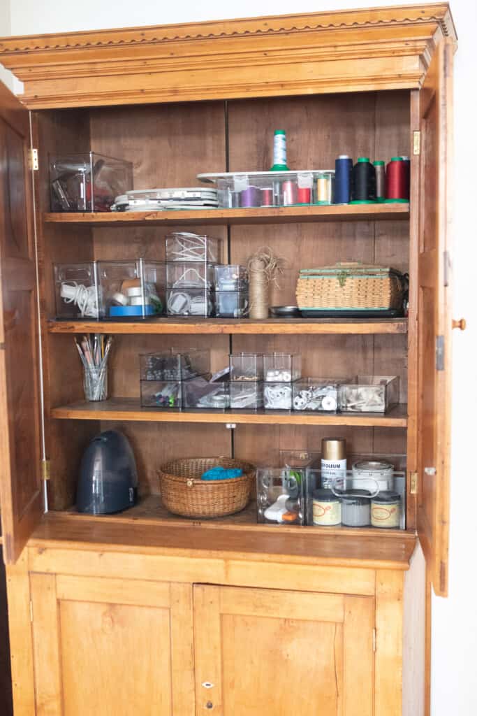 antique wooden craft cabinet organized with clear bins to make it easy to see what is in each bin.
