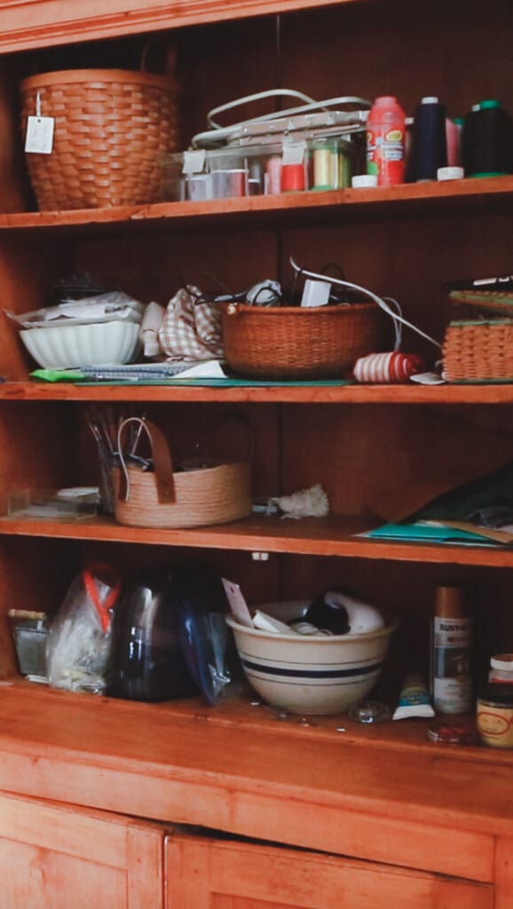 Disorganized crafts in a cabinet with some bowls and baskets to offer some type of organization