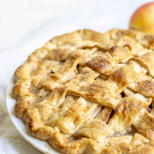 a baked pie in a white pie plate on a marble counter.