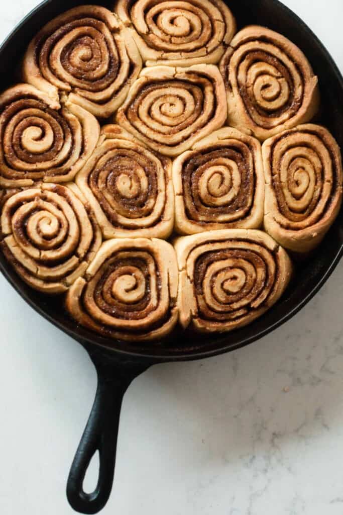 einkorn cinnamon rolls in a cast iron skillet on a white countertop