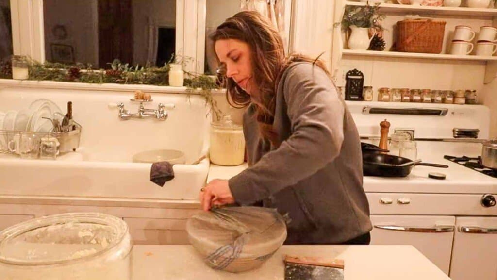 woman placing a banneton basket with bread dough into a plastic grocery bag