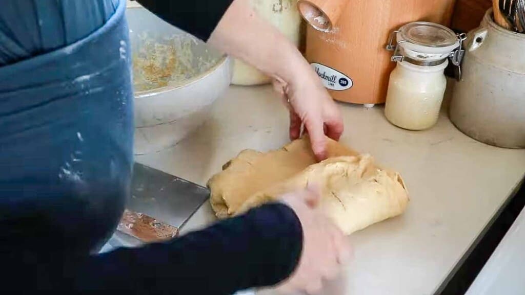 woman stretching and folding einkorn sourdough bread dough on a white quartz countertop
