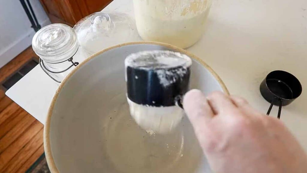 adding einkorn flour to a stoneware bowl