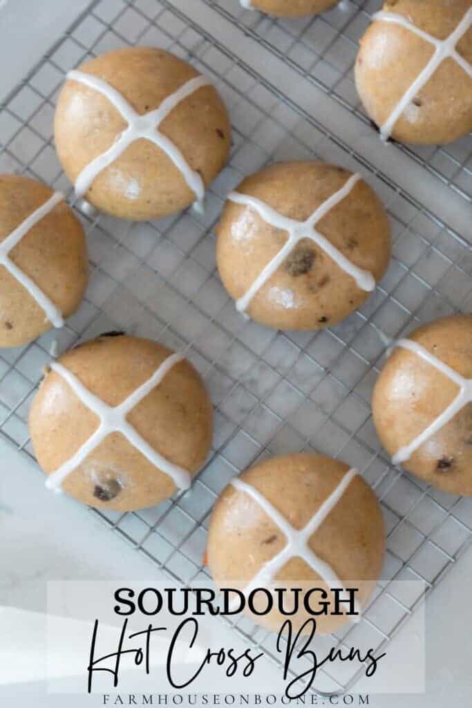 overhead photo of sourdough hot cross buns on a white rack on a quartz countertop