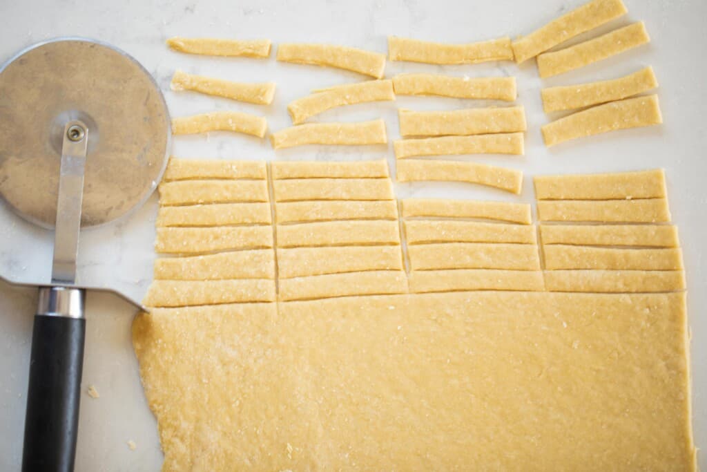 homemade noodles rolled out and half the dough is cut into small noodles for soup